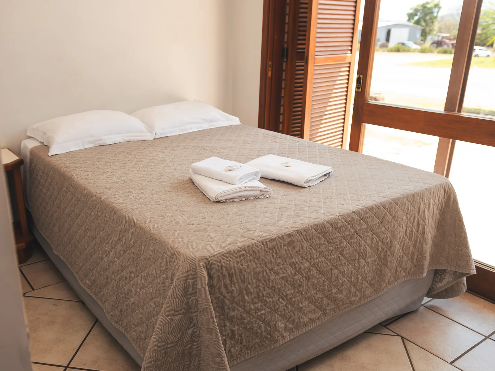 Cama de casal com toalhas dobradas em Apartamento Econômico do Sítio Hotel & Eventos em São Pedro do Sul