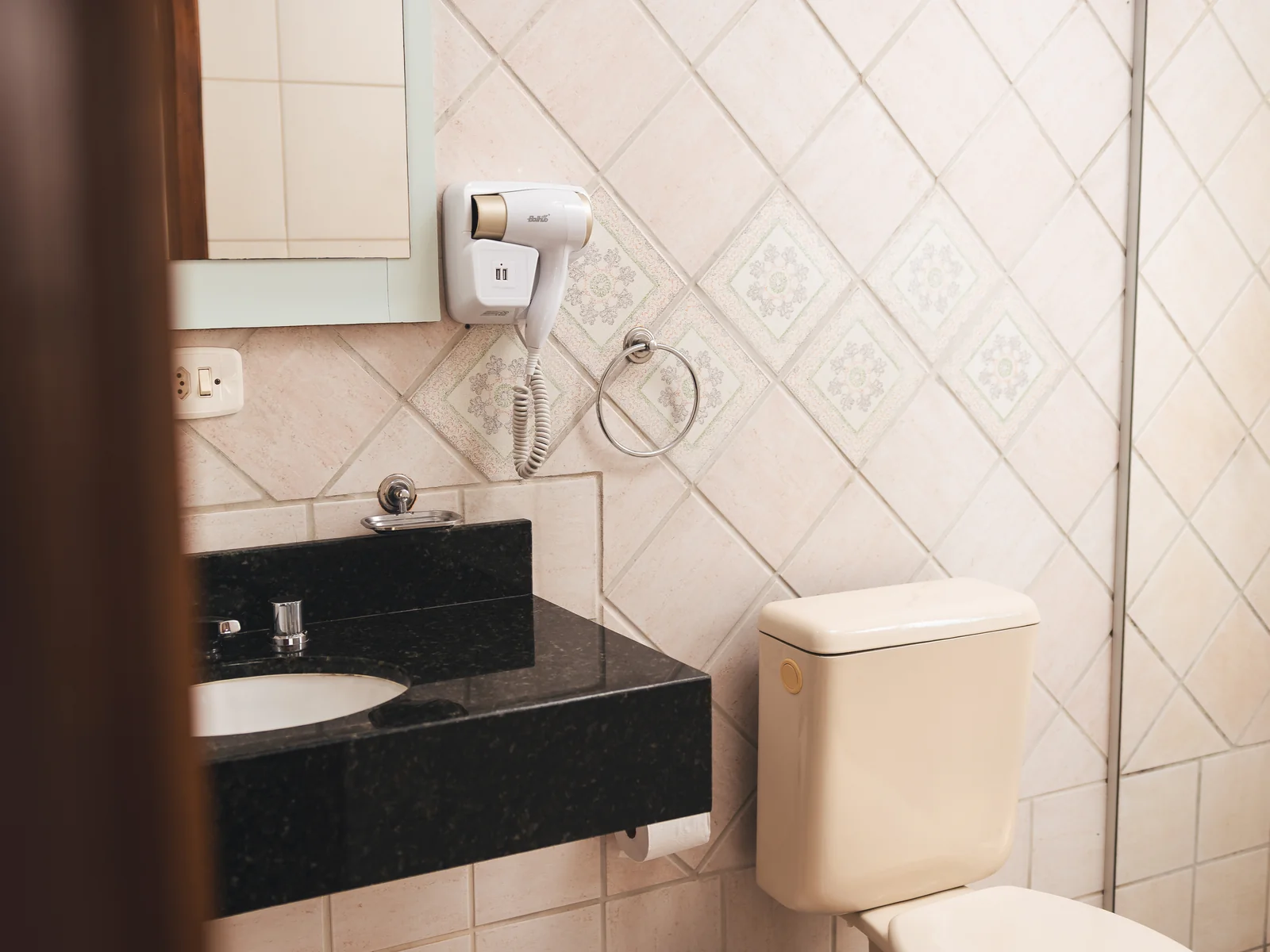 Banheiro de Apartamento Superior com secador de cabelos, bancada de granito e vaso sanitário