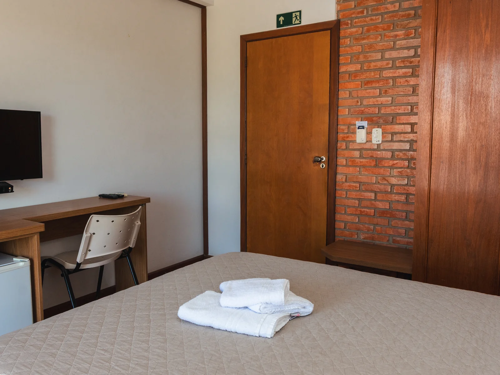 Apartamento Superior com cama de casal, mesa de trabalho e parede de tijolos em São Pedro do Sul
